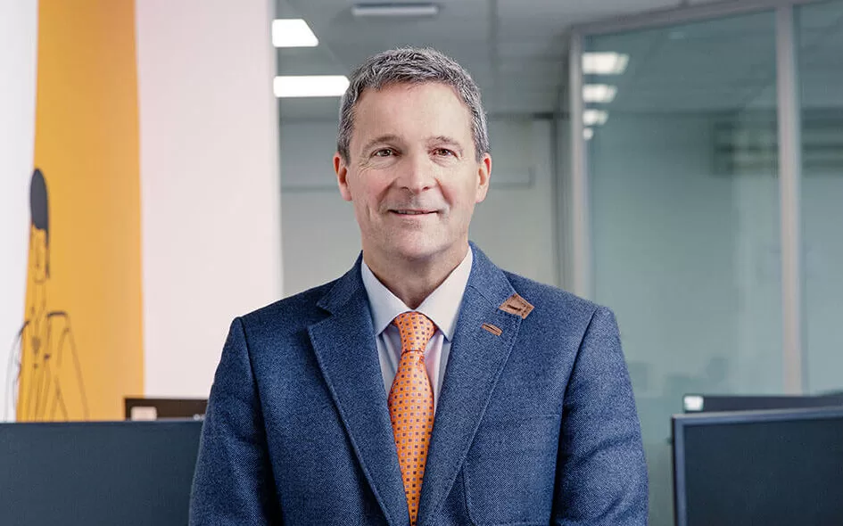 A portrait image of Nunzio Quacquarelli, Founder and President of QS, wearing a blue suit with an orange tie.