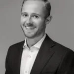 A black and white portrait image of Matteo Quacquarelli wearing a suit and smiling into the camera.